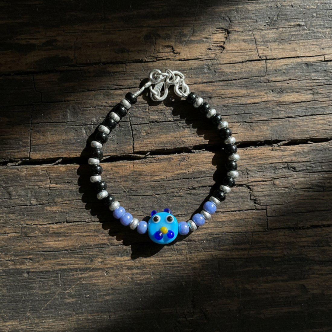 Charming Black and Silver Beaded Bracelet with Whimsical Blue Cartoon Glass Centerpiece.