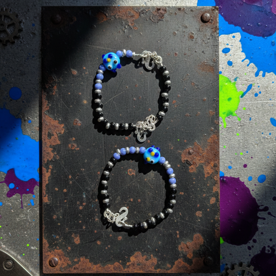 Charming Black and Silver Beaded Bracelet with Whimsical Blue Cartoon Glass Centerpiece.