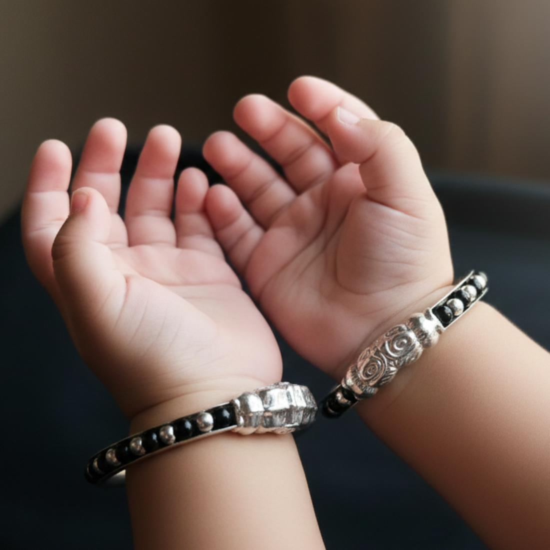 Ornate silver-toned baby kada bracelet with black bead accents.