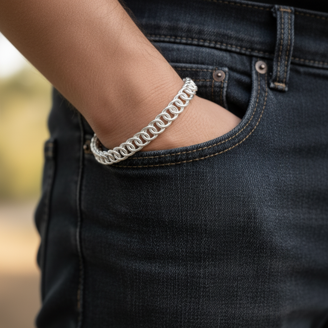 Elegant silver chainmail bracelet on a sunlit wooden surface.