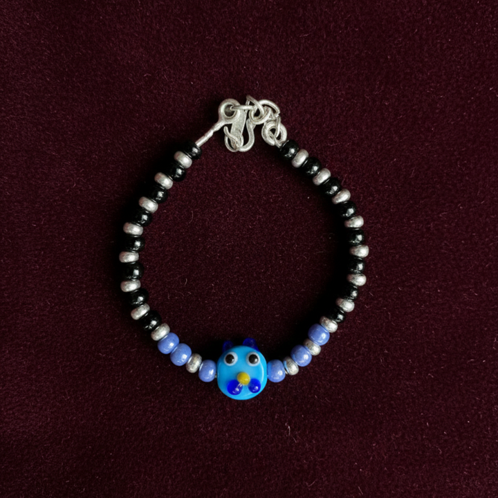 Charming Black and Silver Beaded Bracelet with Whimsical Blue Cartoon Glass Centerpiece.