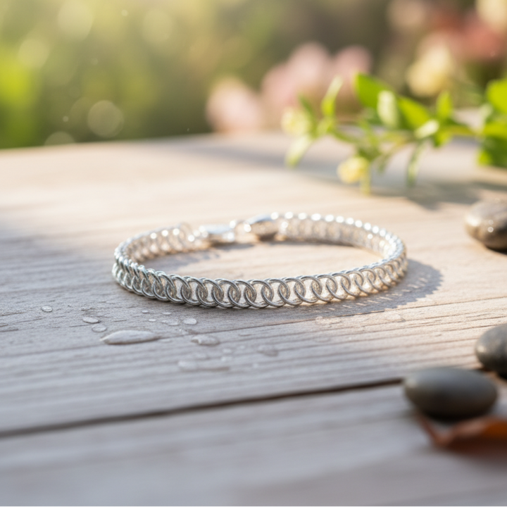 Elegant silver chainmail bracelet on a sunlit wooden surface.