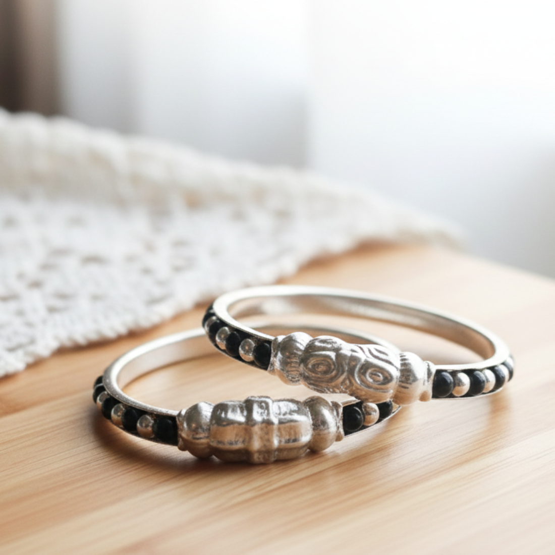 Ornate silver-toned baby kada bracelet with black bead accents.