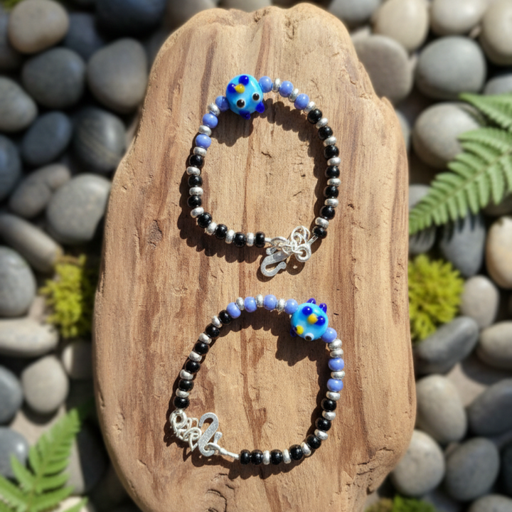 Charming Black and Silver Beaded Bracelet with Whimsical Blue Cartoon Glass Centerpiece.